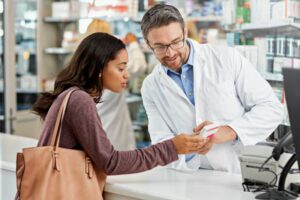 Apotheker berät Kundin zu originalen Hochpreisern am HV-Tisch